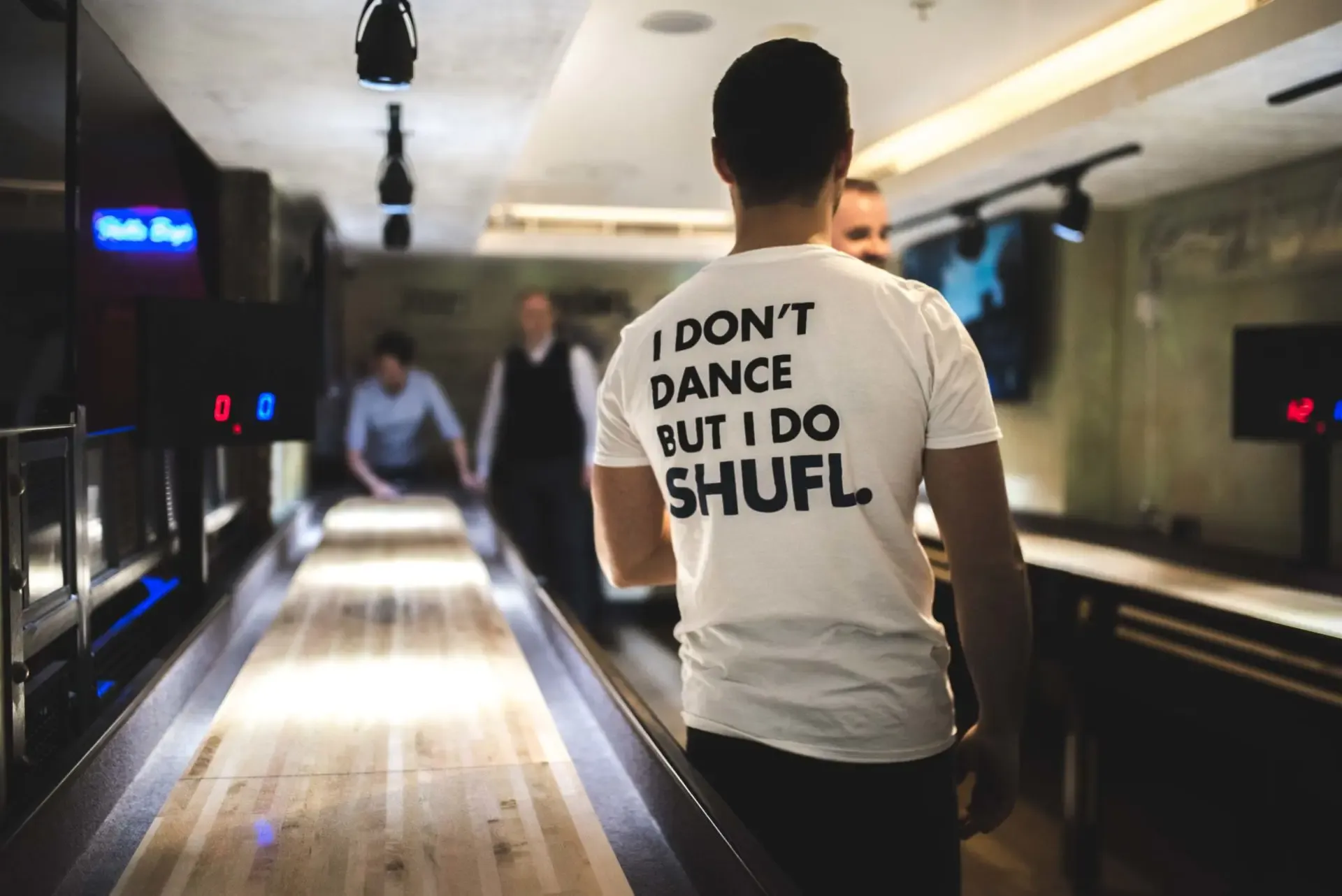 A player walking away from camera by shuffleboard